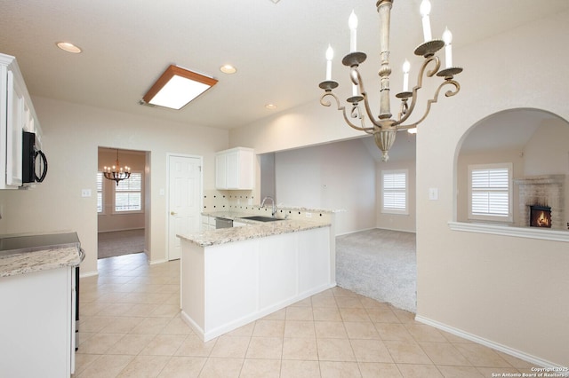 kitchen with an inviting chandelier, white cabinetry, pendant lighting, and light stone countertops