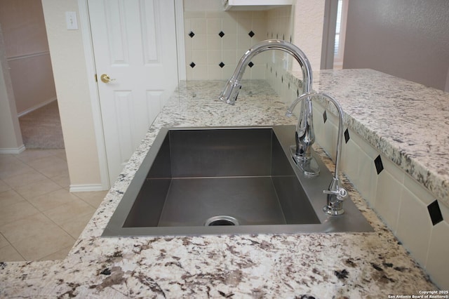 interior details featuring tasteful backsplash, light stone countertops, and sink