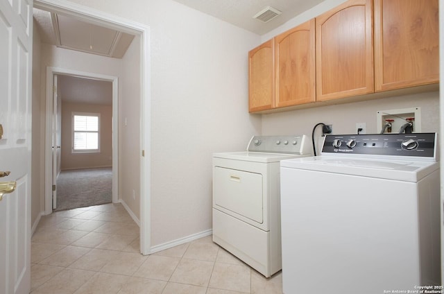 clothes washing area featuring cabinets, washer and dryer, and light tile patterned floors