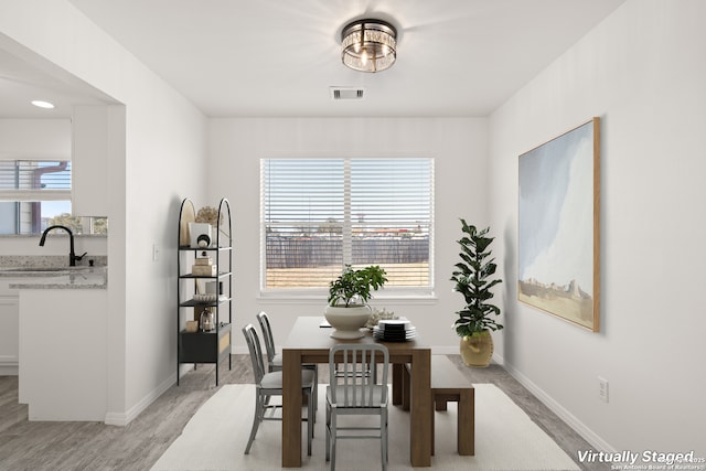 dining area featuring sink, light hardwood / wood-style flooring, and a healthy amount of sunlight