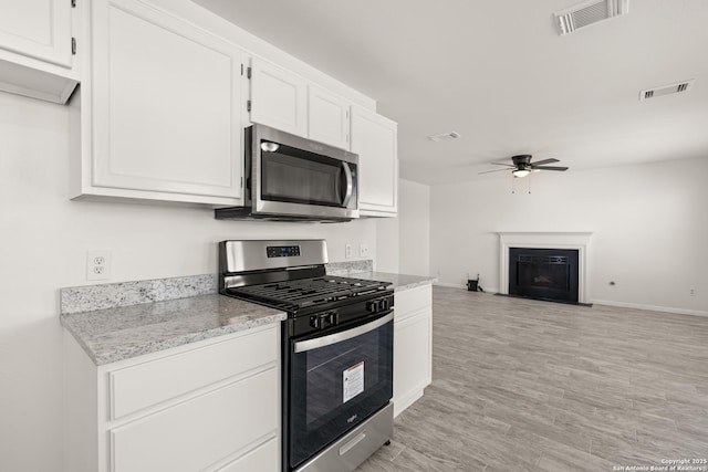 kitchen featuring ceiling fan, stainless steel appliances, light hardwood / wood-style flooring, and white cabinets