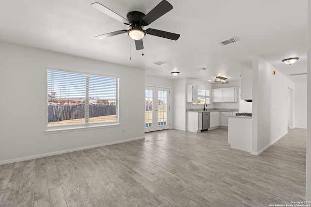 unfurnished living room with french doors, ceiling fan, sink, and light wood-type flooring