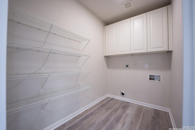 laundry area featuring gas dryer hookup, cabinets, light hardwood / wood-style flooring, washer hookup, and hookup for an electric dryer