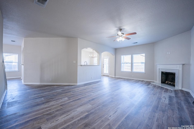 unfurnished living room featuring plenty of natural light, dark hardwood / wood-style floors, and ceiling fan with notable chandelier