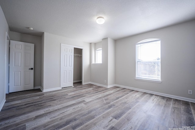 unfurnished bedroom with hardwood / wood-style flooring, a closet, and a textured ceiling