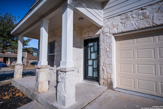 view of exterior entry with a garage and covered porch