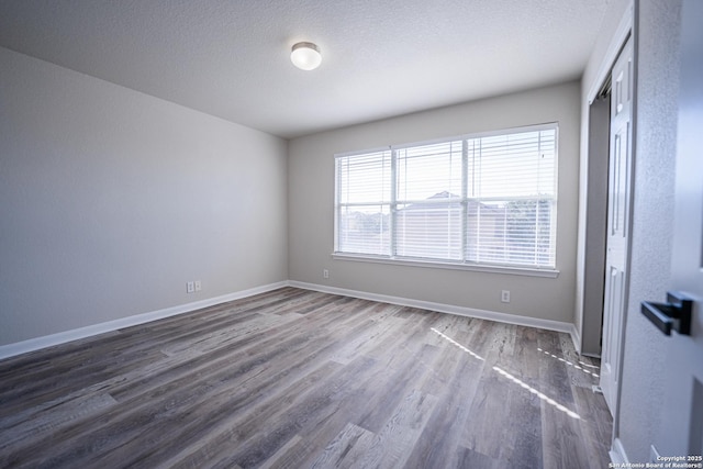 spare room featuring dark wood-type flooring and a textured ceiling