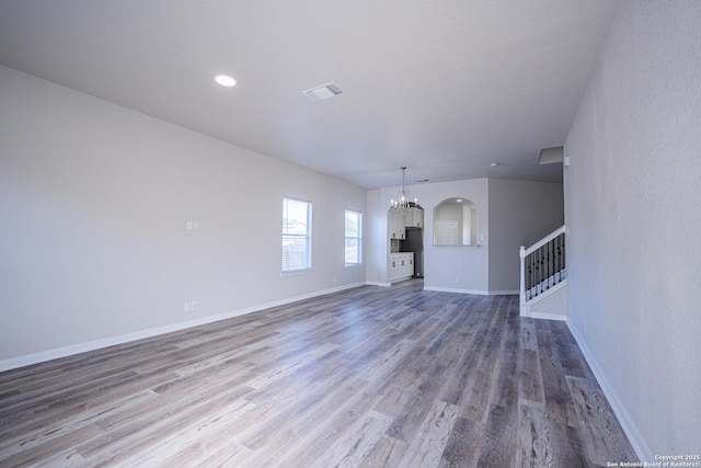 unfurnished living room with hardwood / wood-style flooring and a chandelier