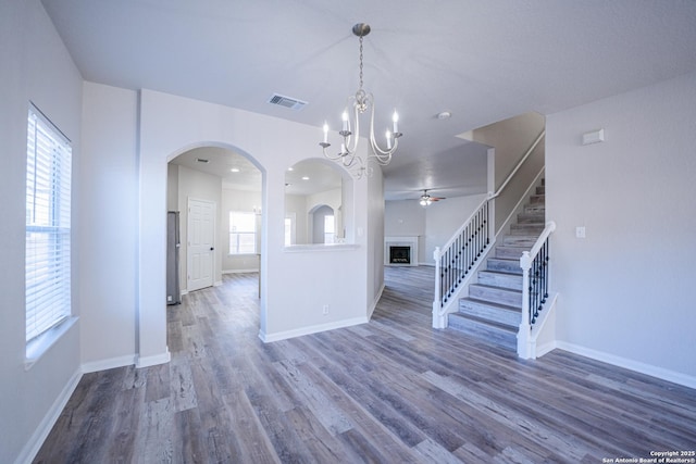 interior space featuring ceiling fan with notable chandelier and dark wood-type flooring