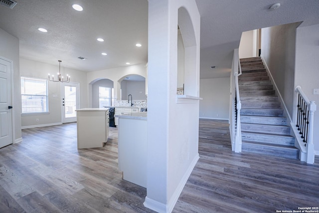 kitchen featuring dark hardwood / wood-style floors, pendant lighting, backsplash, and kitchen peninsula