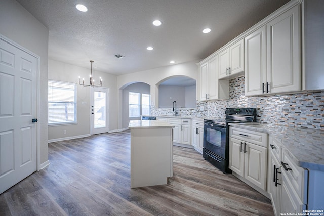 kitchen featuring white cabinetry, black / electric stove, pendant lighting, and hardwood / wood-style floors