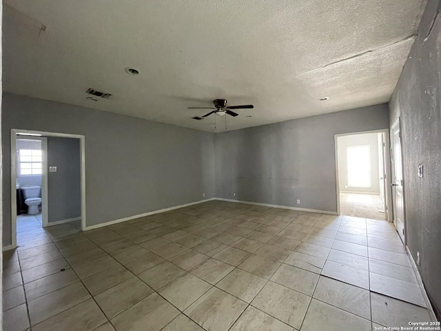 tiled empty room with ceiling fan and a textured ceiling