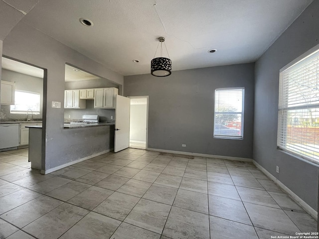 kitchen featuring sink, hanging light fixtures, range, light tile patterned floors, and white dishwasher