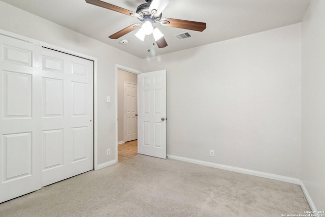 unfurnished bedroom featuring ceiling fan, a closet, and light carpet