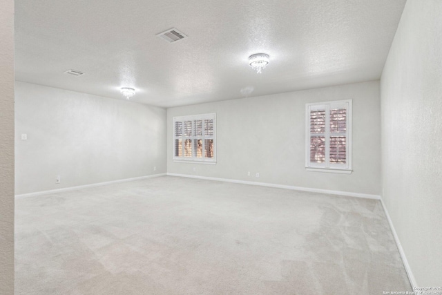 unfurnished room with light colored carpet and a textured ceiling