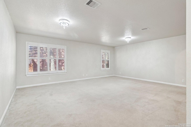 unfurnished room featuring light carpet and a textured ceiling