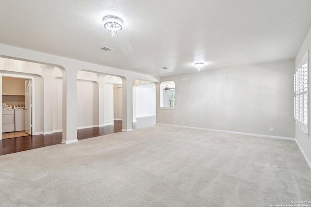 spare room with washer and clothes dryer, a textured ceiling, and carpet