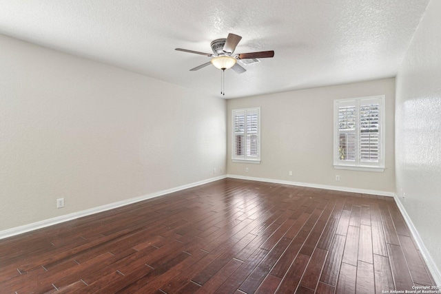 empty room with a wealth of natural light, dark wood-type flooring, a textured ceiling, and ceiling fan