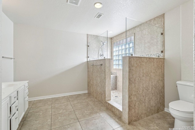 bathroom featuring toilet, a textured ceiling, a tile shower, vanity, and tile patterned flooring