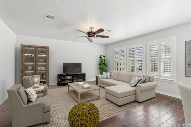 living room featuring ceiling fan, dark hardwood / wood-style flooring, and a textured ceiling