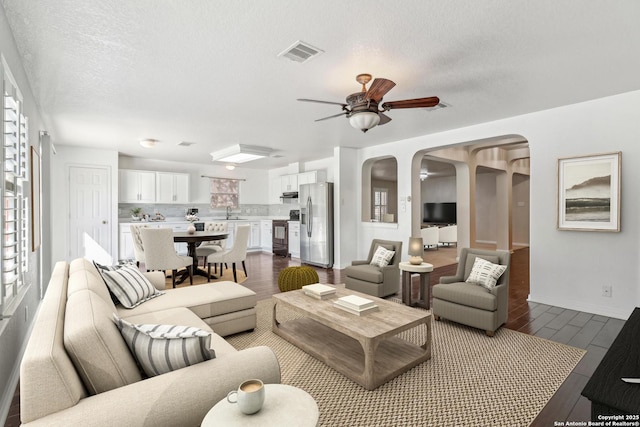 living room with ceiling fan, hardwood / wood-style flooring, sink, and a textured ceiling