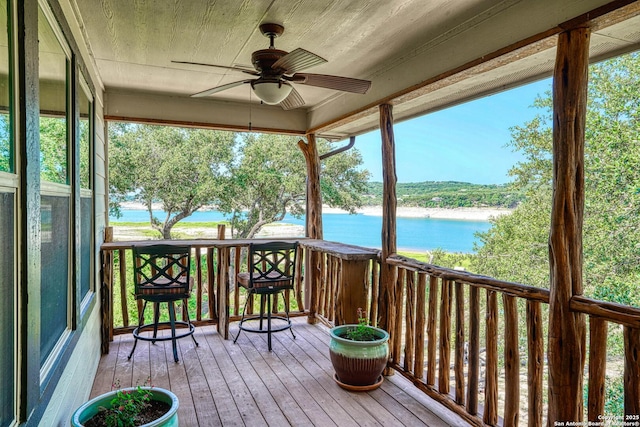 deck with ceiling fan and a water view