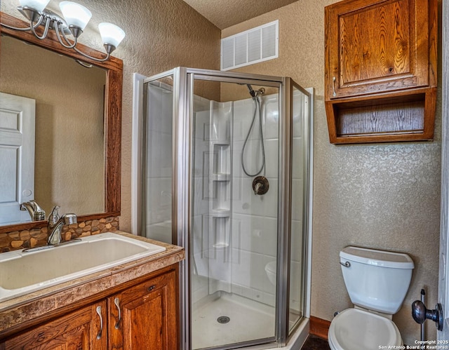 bathroom featuring vanity, a shower with door, toilet, and a textured ceiling