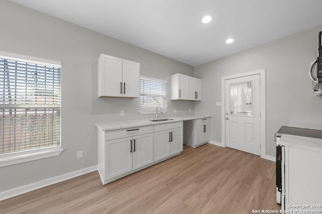 kitchen with electric stove, light wood-type flooring, sink, and white cabinets