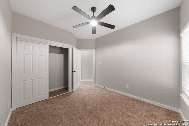 unfurnished bedroom with vaulted ceiling, carpet flooring, ceiling fan, and a closet