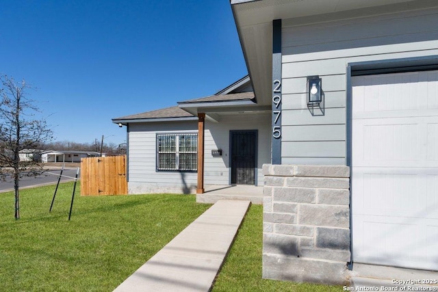 doorway to property featuring a garage and a lawn