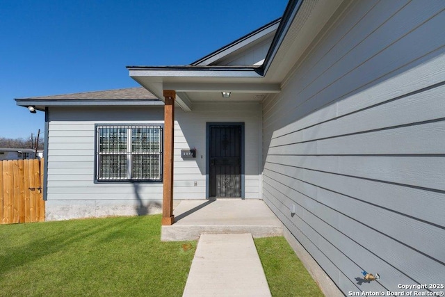 view of exterior entry with a lawn and a patio