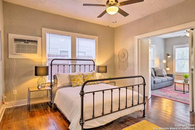 bedroom featuring ceiling fan, dark hardwood / wood-style floors, a textured ceiling, and an AC wall unit