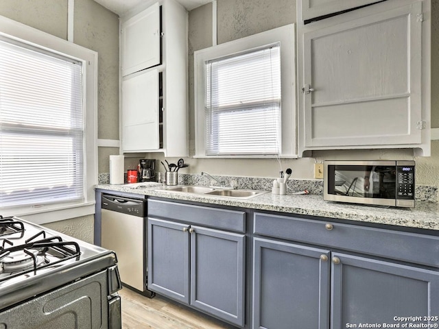 kitchen with stainless steel appliances, sink, light wood-type flooring, and gray cabinets