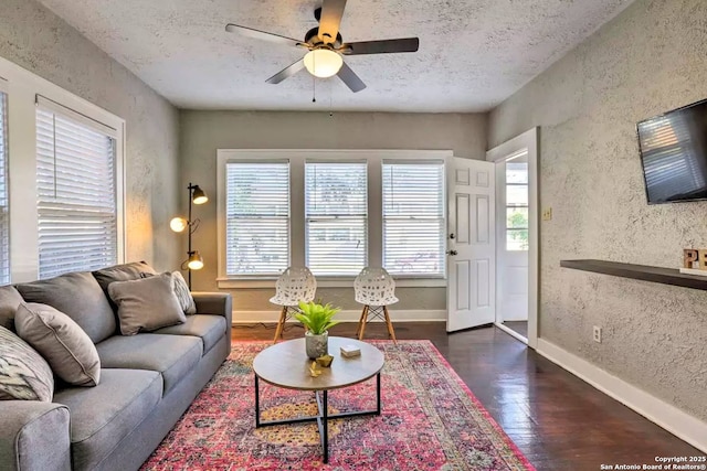 living room with dark hardwood / wood-style flooring, ceiling fan, and a textured ceiling