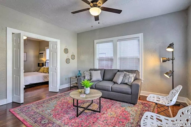 living room featuring dark wood-type flooring, ceiling fan, and a textured ceiling