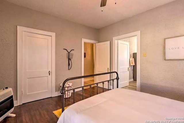 bedroom with ceiling fan, heating unit, and dark hardwood / wood-style flooring