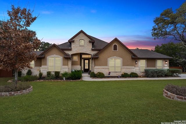 french country inspired facade featuring a yard