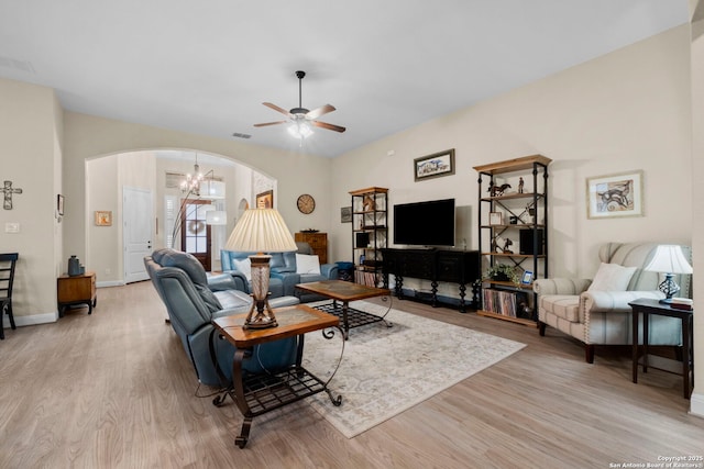 living room featuring ceiling fan with notable chandelier and light hardwood / wood-style flooring