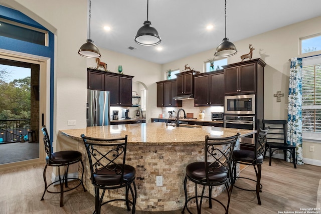 kitchen with pendant lighting, sink, appliances with stainless steel finishes, a kitchen bar, and decorative backsplash