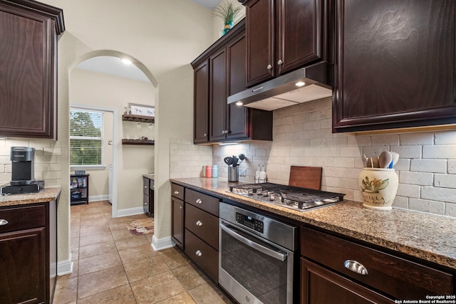 kitchen featuring appliances with stainless steel finishes, backsplash, light tile patterned floors, dark brown cabinetry, and light stone countertops