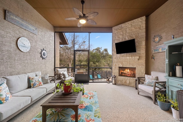 sunroom / solarium featuring ceiling fan, wood ceiling, and an outdoor stone fireplace