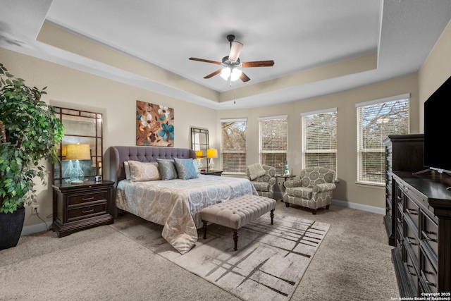 carpeted bedroom with a raised ceiling and ceiling fan