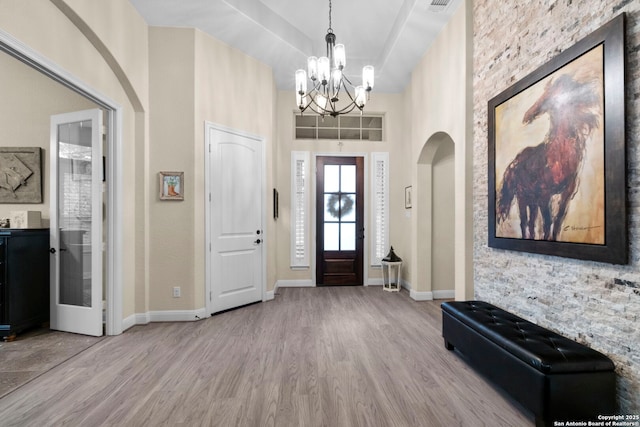 entrance foyer featuring an inviting chandelier, a high ceiling, and light wood-type flooring