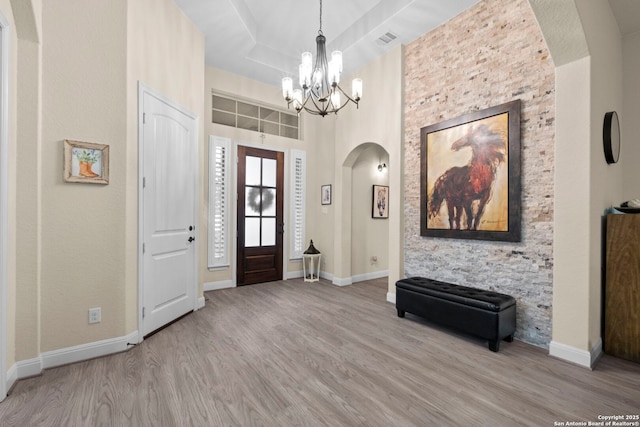 entrance foyer with a chandelier, a high ceiling, and light wood-type flooring