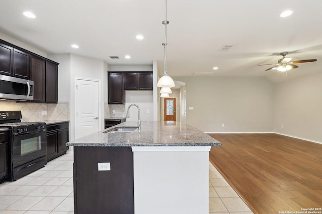 kitchen featuring pendant lighting, a kitchen island with sink, sink, and black gas range oven