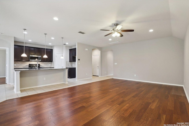 unfurnished living room with ceiling fan, sink, vaulted ceiling, and light hardwood / wood-style flooring