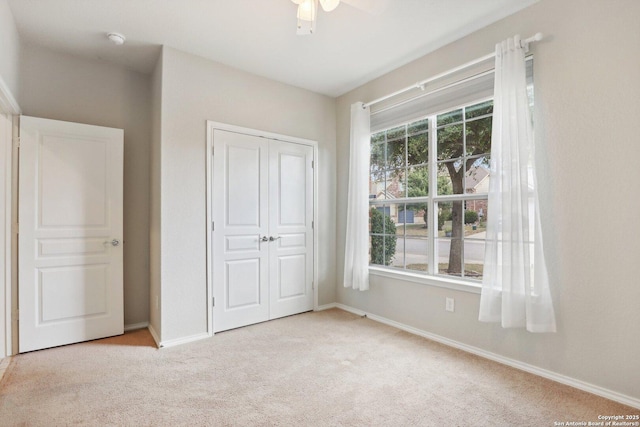 unfurnished bedroom with light carpet, ceiling fan, and a closet