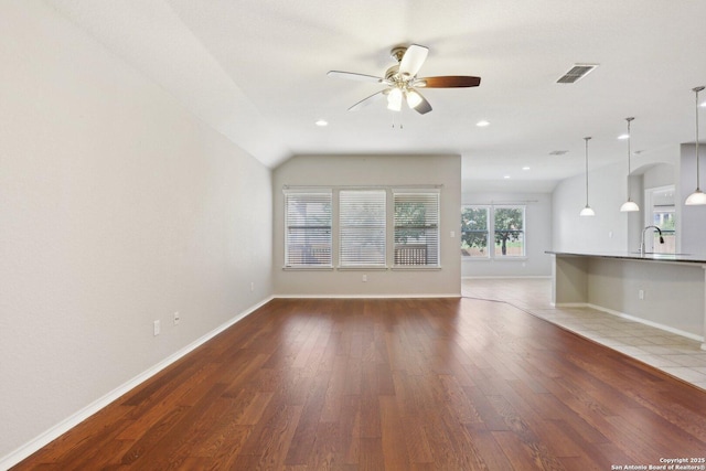 unfurnished living room with ceiling fan, sink, dark hardwood / wood-style flooring, and vaulted ceiling