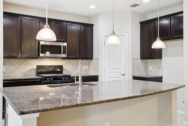 kitchen featuring tasteful backsplash, black range with gas stovetop, hanging light fixtures, and dark stone countertops