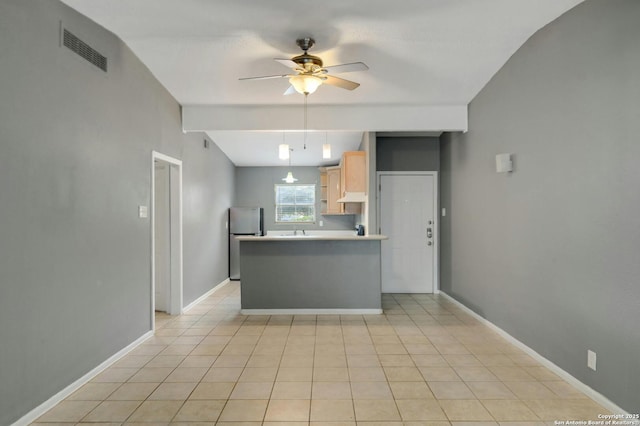 kitchen with vaulted ceiling, light brown cabinetry, stainless steel refrigerator, light tile patterned floors, and ceiling fan